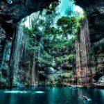 Cenote en Homún, Yucatán, con aguas cristalinas y raíces colgantes.
