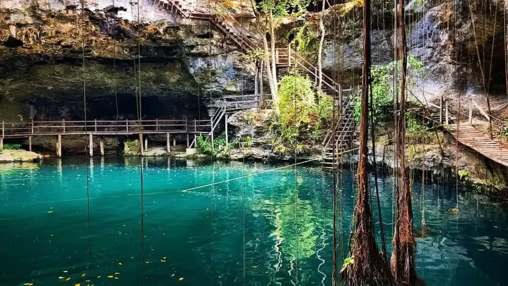 Cenote Xlacah en Dzibilchaltún, Yucatán, con aguas cristalinas y vegetación exuberante.