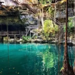 Cenote Xlacah en Dzibilchaltún, Yucatán, con aguas cristalinas y vegetación exuberante.